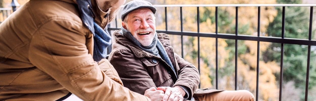 Lächelnder älterer Herr mit Schiebermütze im Gespräch